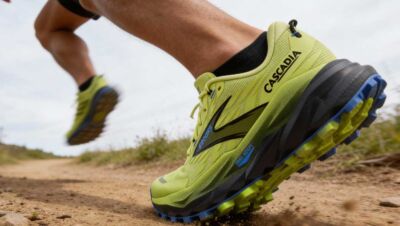 Corredor con Brooks Cascadia 20 en terreno de montaña, con suela Vibram Megagrip en primer plano