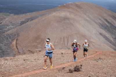 Corredores de trail running atravesando paisaje volcánico en Lanzarote durante una carrera