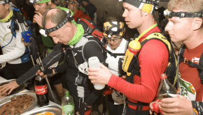 Corredor de trail running tomando cafeína durante avituallamiento una ultra en montaña