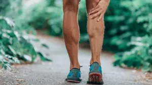 Corredor de trail running con calambres musculares durante una carrera de montaña