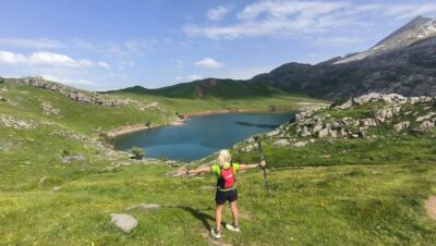 Corredor en la Marcha de los Tres Ibones con ibón al fondo, Pirineo aragonés