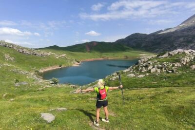 Corredor en la Marcha de los Tres Ibones con ibón al fondo, Pirineo aragonés